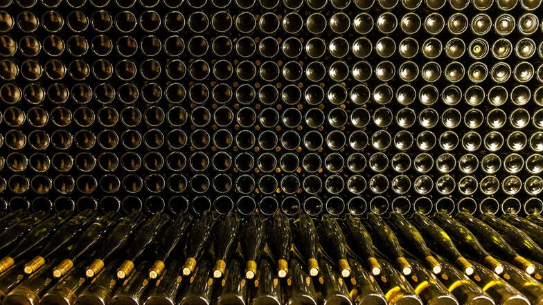 Symbolbild: Fertig befüllte Weinflaschen liegen gestapelt im Keller eines Weingutes.