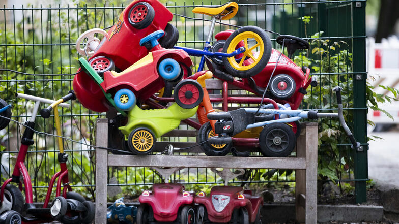 Symbolbild: Bobby-Cars, andere Spielautos und Gefährte für Kinder liegen angeschlossen vor einer Kita auf einem Stapel. Wie im Außenbereich Kinder getrennt werden, wird je Döbelner Kita individuell organisiert.
