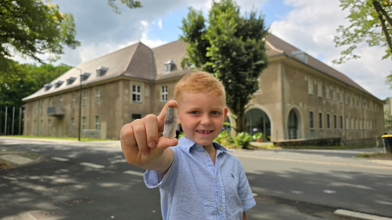 Kinderreporter Eddie mit seinem bronzezeitlichen Steinfund vor dem 			Landesamt für Archäologie in Dresden-Klotzsche.