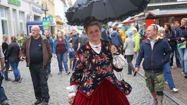 Karin von der Westerntanzgruppe ist mit einem Kostüm von 1855 auf der Hauptstraße unterwegs.  Den Schirm brauchte es am Nachmittag - ab und an tröpfelte es tatsächlich ein bisschen.