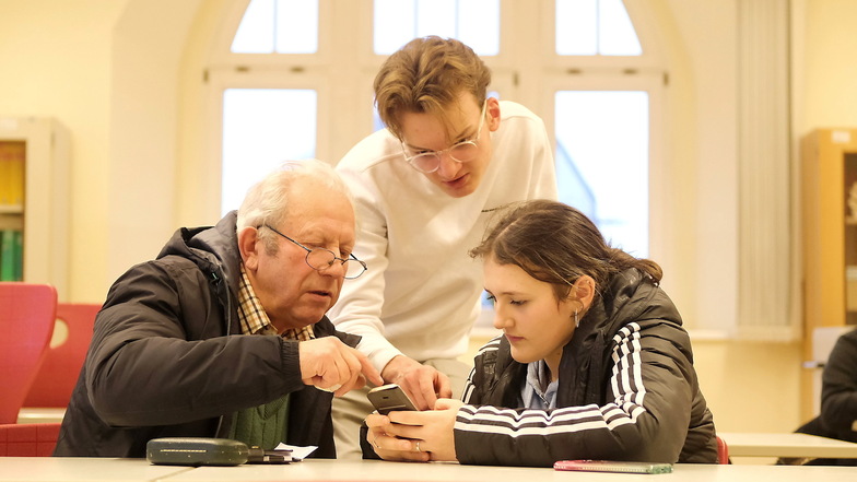 Mediensprechstunde im Franziskaneum: Schüler Elijan und Schülerin Michelle helfen einem älteren Herren bei der Bedienung des Smartphones.