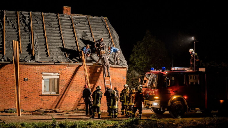 Niedersachsen, Berumerfehn: Feuerwehrleute und Helfer reparieren das Dach eines beschädigten Hauses.