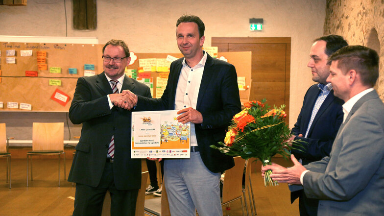 Riesas Oberbürgermeister Marco Müller (CDU, 2.v.l.) nahm stellvertretend den Gewinn aus dem Wettbewerb "Ab in die Mitte" von  IHK-Geschäftsführer Thomas Ott entgegen. 