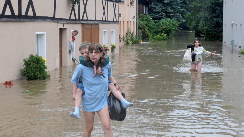 Am 7. August 2010 in Rosenthal, einem Ortsteil von Hirschfelde, verlässt Marita Zeiner, auf dem Rücken ihr Sohn Dominic, das geflutete Haus an der Neiße.