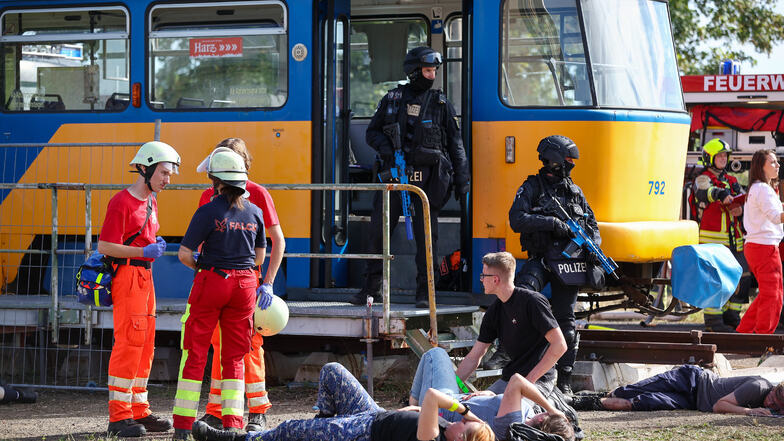Polizisten sichern während einer Terrorübung eine Straßenbahn nach einem Terroranschlag, während sich Rettungskräfte einen Überblick verschaffen.