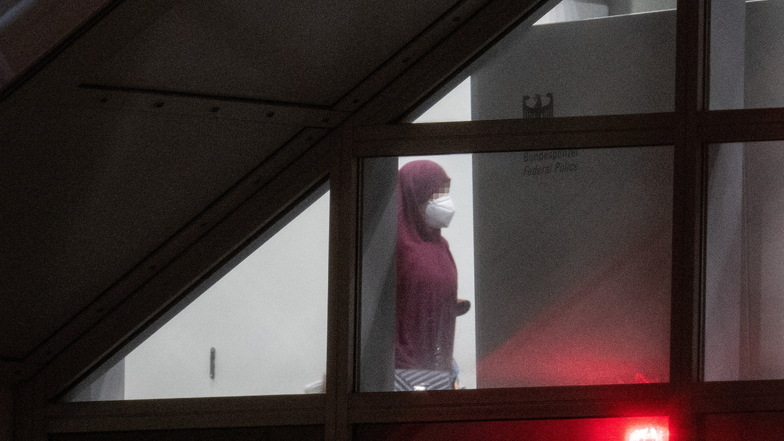 Eine verschleierte Frau mit einer Maske betritt aus der Gangway einer Chartermaschine heraus einen abgeschirmten Bereich der Bundespolizei am Flughafen Frankfurt.