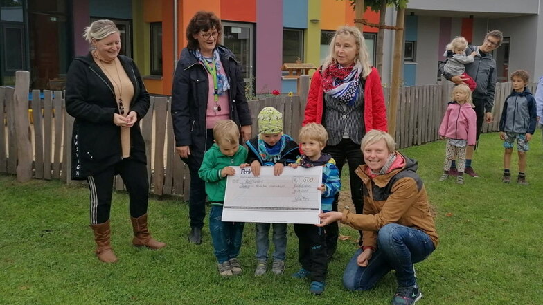 Sabine Merz (2.v.r.) von der Bautzener R+V-Generalagentur überreicht den Kinder vom Kinderhaus Sonnenschein in Bischofswerda einen symbolischen Scheck.