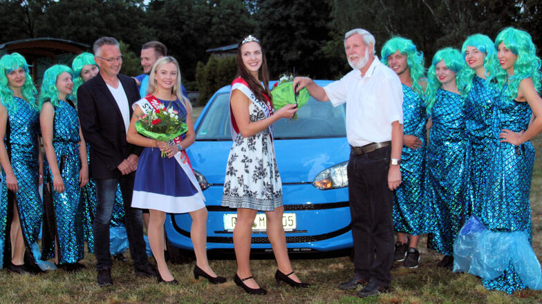 Die neue Nixe Yasmin Kunze (helles Kleid) erhält von Volkmar Kirsten vom Autohaus Hercher den Schlüssel für einen VW up! zur zweijährigen kostenlosen Nutzung. Links daneben im blau-weißen Kleid die bisherige Nixe Heidi Orisch.