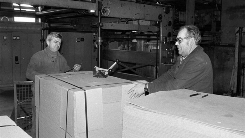 Die letzten Mitarbeiter Heinz Habla (r.) und Manfred Fetting bei der manuellen Umreifung einer Kartonpalette. Dahinter die Klebemaschine. Kartonbahnen wurden zu dicken Buchbahnen zusammengeklebt. Dieser Buchdeckel-Karton fand bei Kinderbüchern Verwendung.