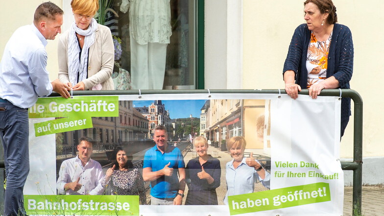 DDV-Elbland-Geschäftsführerin Petra Gürtler (r.) befestigt mit den beiden Händlern, Susan Gommlich und Uwe Marx, ein Transparent am Geländer vor der Lößnitzperle.