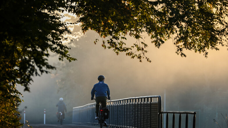 Zwei Radfahrer sind bei Morgennebel in Leipzig unterwegs: Der September präsentiert sich derzeit mit frischen Nächten und sonnigen Tagen.