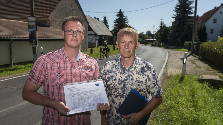 Tom Flach (l.) und Frank Lehmann stehen in Ludwigsdorf mit einer Unterschriftenliste zum Thema Straßenausbaubeitragssatzung.