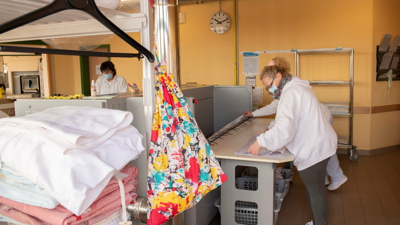 Simone Bastian und Petra Stahl (v.l.) arbeiten an der Wäschemangel. Für Firmen und private Auftraggeber wird hier gewaschen.
