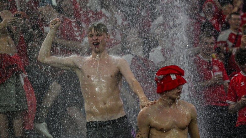 Fans von Dänemark tanzen im Regen während einer Spielunterbrechung in Dortmund.