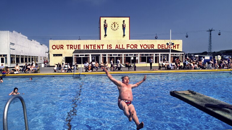 In der Fotografie von Barry Lewis aus dem Jahr 1982 lässt sich ein Mann vergnügt ins Wasser plumpsen. Der Satz „Our true intent is all for your delight“ wurde Shakespeares „Sommernachtstraum“ entlehnt.