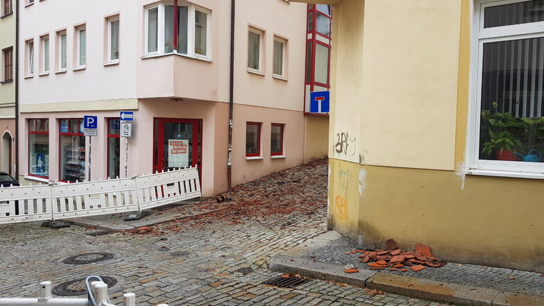 Vom Ruß verfärbte Dachziegelteile liegen am Sonntagmittag vor dem Brandhaus in der Bautzener Innenstadt.