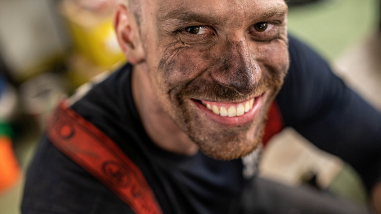 Ein tschechischer Feuerwehrmann lächelt mit Ruß verschmiertem Gesicht.