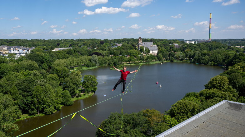 In bis zu 50 Metern Höhe balanciert Jens Decke auf einer Highline über dem Schlossteich in Chemnitz. Die 630 Meter lange Slackline ist zwischen dem Turm der Schlosskirche (hinten) und einem Hochhaus gespannt und gilt deutschlandweit als längste Line im ur