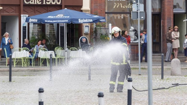 Ein Feuerwehrmann befeuchtet für die nächste Szene den Obermarkt.