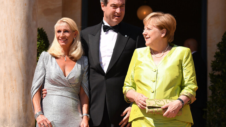 Bundeskanzlerin Angela Merkel (CDU, r) kommt zusammen mit dem Bayerischen Ministerpräsidenten Markus Söder (CSU) und dessen Frau, Karin Baumüller-Söder, zum Beginn der Bayreuther Festspiele 2019.
