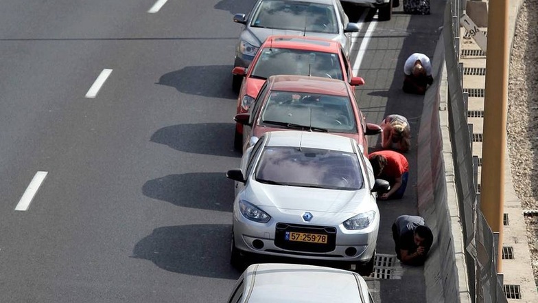 Raketenalarm inTel Aviv: Israelis suchen Schutz neben ihren Autos. Bislang gibt es keine Berichte von Opfern in Israel.
