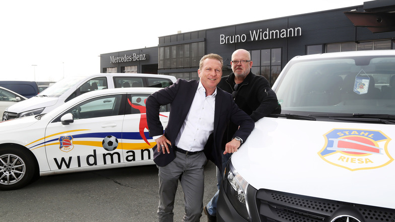 Jens Bergk (l.), Geschäftsführer des Autohauses Widmann in Zeithain, und Falko Obenaus, Geschäftsführer der Stahl Riesa Sport GmbH, vor den drei neuen Autos für die BSG Stahl Riesa.