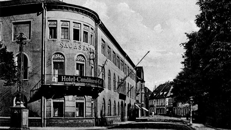Auf diesem historischen Foto ist sein oberer Teil als Strommast 1929 vor dem Sachsenhof zu sehen.