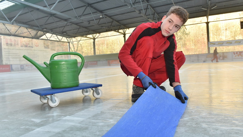 Lehrling Gustav Herzog bringt auf der Eisfläche im Freitaler Hains eine Bahn aus Krepppapier auf, die später ein Teil der Spielfeldmarkierung im Eis wird.