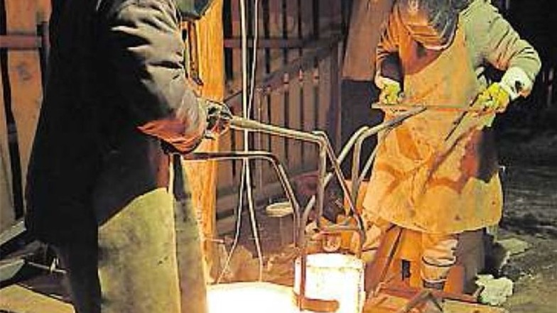 Tomasz und sein Mitarbeiter gießen die 1200 Grad Celsius heiße Bronze in den aufwendig vorbereiteten hohlen Mantel.