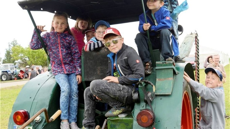 Beim Traktorentreffen spielen Kinder auf einem Oldtimer-Traktor - und haben sichtlich Spaß.