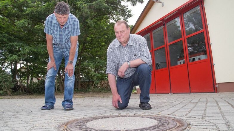 Vor der Feuerwehr in Mücka misst der Abwasserverband regelmäßig Schwefelwasserstoffwerte in der Kanalisation. Für die interessieren sich selbstverständlich auch Anwohner wie Frank Beier (links) und Bernd Hilgenfeld.