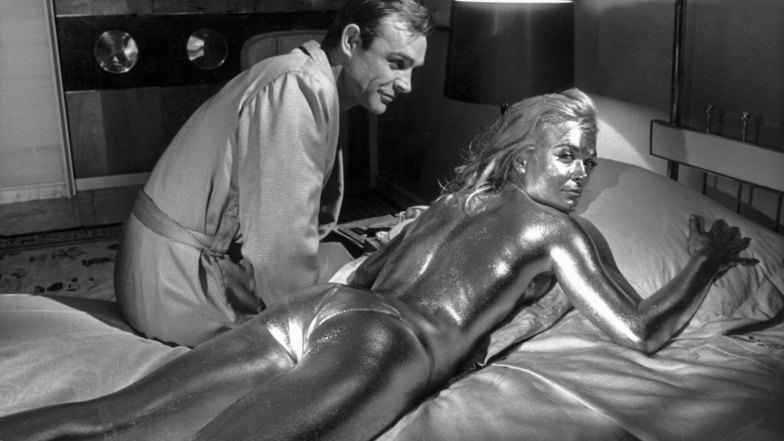 Sean Connery in der Rolle des James Bond und die goldüberzogene Shirley Eaton, aufgenommen während der Dreharbeiten zum James-Bond-Film "Goldfinger" im Jahre 1964.