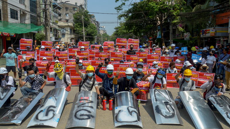 Demonstranten, die in Yangon gegen den Militärputsch demonstrieren, versammeln sich und zeigen Plakate. Die Junta hat in Teilen der größten Stadt des Landes das Kriegsrecht verhängt.