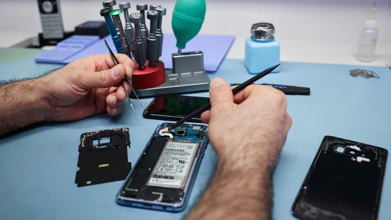 Ein Techniker repariert ein Smartphone mit defektem Display.