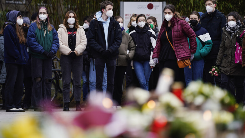 Menschen legen vor einem Gebäude der Universität Heidelberg Blumen und Kerzen an den Wegesrand. Am Montag hatte ein 18 Jahre alter Student mit einer Schrotflinte bei laufender Vorlesung in einem Hörsaal eine Frau getötet und drei Menschen verletzt.