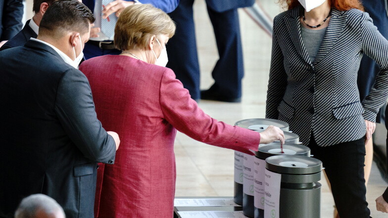 Bundeskanzlerin Angela Merkel (CDU) gibt ihre Stimmkarten bei der Abstimmung über Änderungsanträge bei der Sitzung des Bundestags ab.