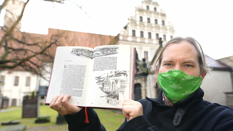 Peter Knüvener mit der Hefftergiebel-Illustration aus dem Grimm'schen Märchenbuch vor der realen Sehenswürdigkeit.