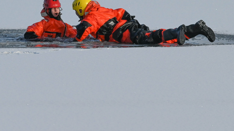 Feuerwehrleute trainieren die Rettung eines Opfers, das auf einem zugefrorenen See eingebrochen ist.