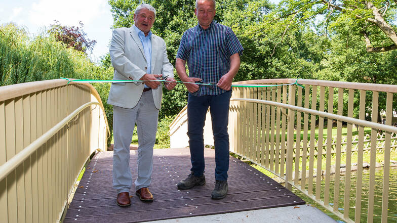 Bürgermeister Peter Mühle (links) und Ronny Göttlich vom Metallbau Göttlich geben die Bogenbrücke im Arthur-Richter-Park wieder frei.