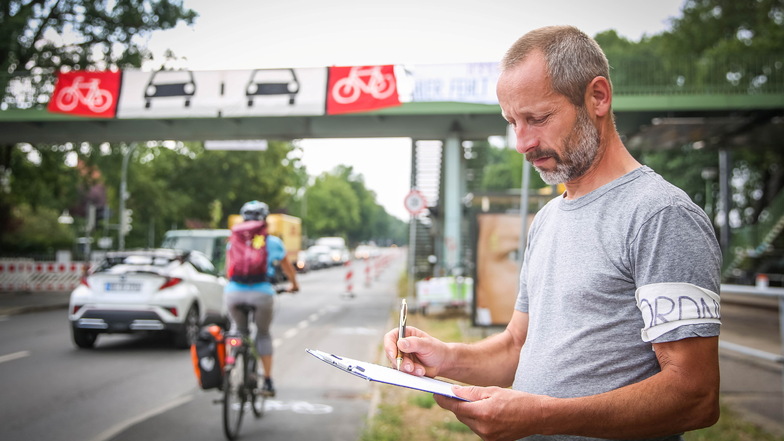 Mathias Greuner von der AG nachhaltig mobil zählt am Pop-Up-Radweg zwischen Fußgängerbücke am Industriegelände und der Heeresbäckerei, wie viele Radfahrende vorbeikommen.