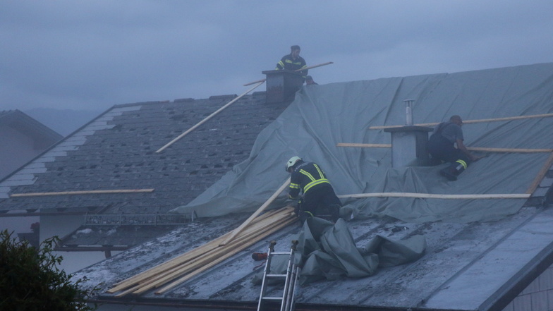 Österreich, Salzburg: Feuerwehrleute arbeiten auf einem beschädigten Dach.