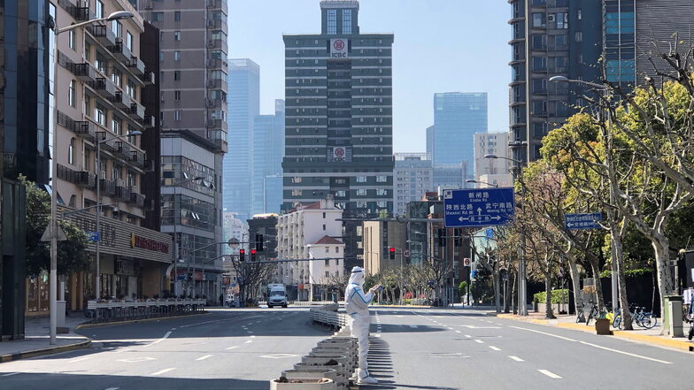 Ein Mann in einem Schutzanzug steht inmitten leerer Straßen in einem abgesperrten Gebiet im Bezirk Jingan im Westen von Shanghai.