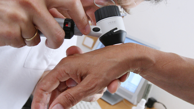Ein Hautarzt untersucht die Haut einer Patientin bei einer Hautkrebs-Früherkennung.