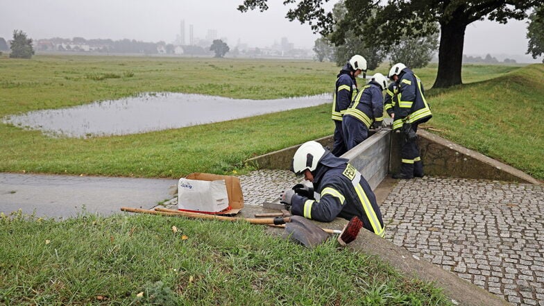 Lückenschluss am Leutewitzer Deich: Riesaer Feuerwehrleute bauen den Flutschutz im Ortsteil ein. Im Hintergrund im Dunst zu sehen: Das Wacker-Chemiewerk in Nünchritz.