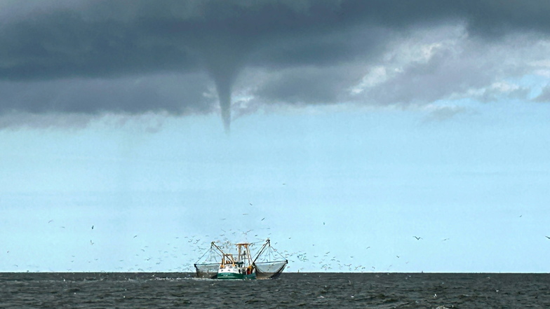 Das von einem Fischerboot aufgenommene Foto zeigt einen entstehenden mutmaßlichen Tornado vor der Nordseeinsel Borkum und ein Fischerboot.