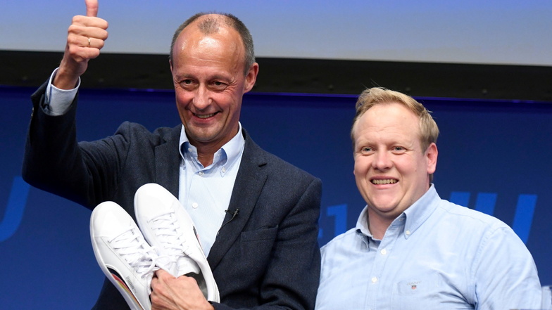 Friedrich Merz (l), früherer CDU/CSU-Fraktionsvorsitzender im Bundestag, bedankt sich neben Tilman Kuban, Vorsitzender der Jungen Union (JU), für das Paar Sneaker, das er beim Auftakt des Deutschlandtages der Jungen Union bekam.