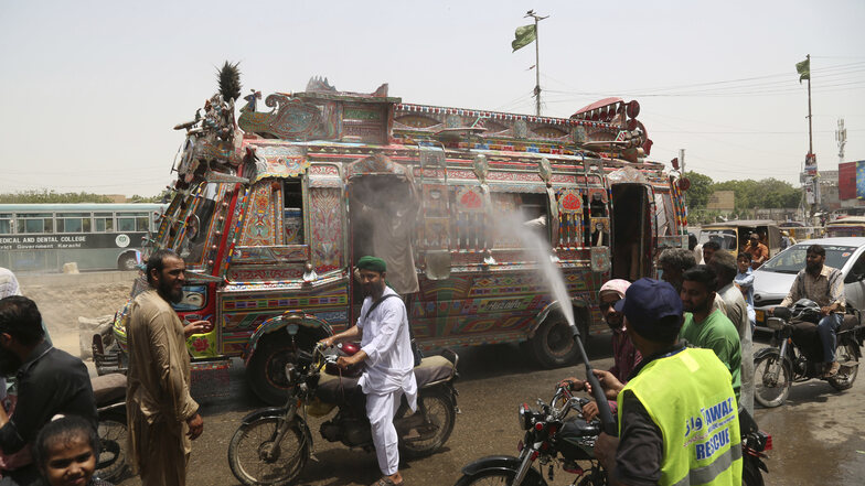 Ein Mann kühlt vorbeifahrende Motorradfahrer bei den hohen Temperaturen ab. In der pakistanischen Stadt Turbat wurde es auch 2017 sehr heiß.