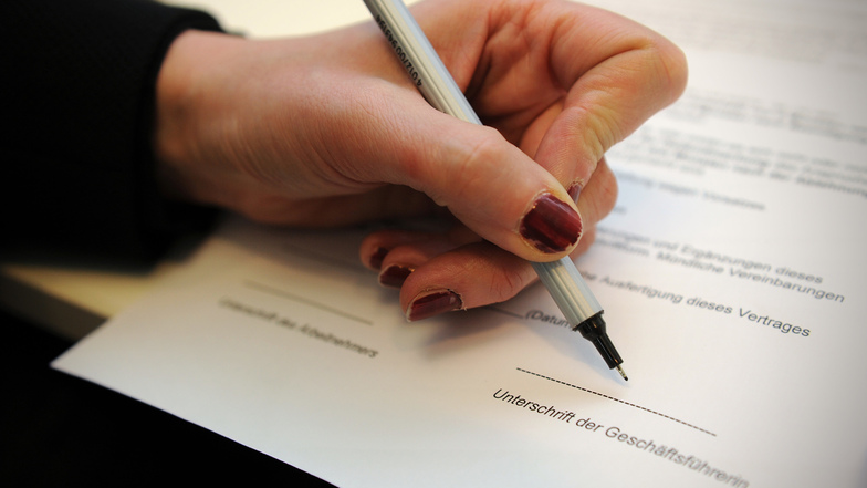 Symbolbild: Eine Frau unterschreibt auf einem Schreibtisch in einem Büro in Berlin einen Arbeitsvertrag