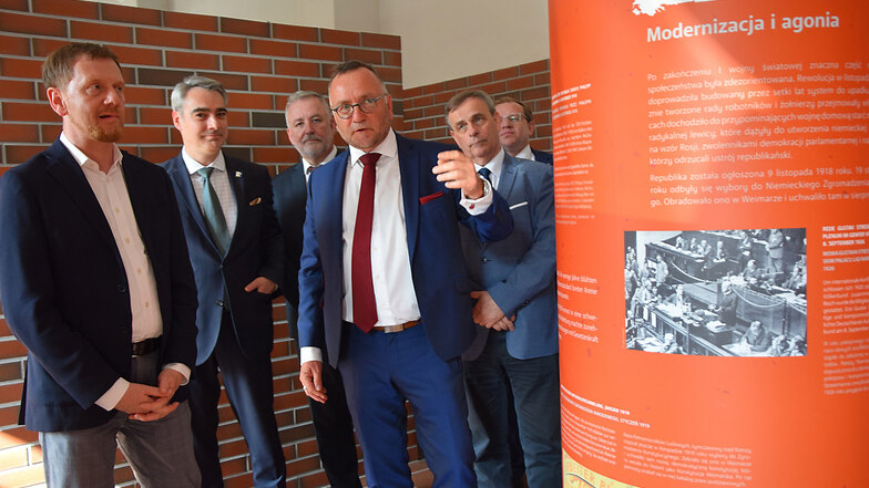 Der sächsische Vertriebenen-Beauftragte Dr. Jens Baumann (roter Schlips) führte Sachsens Ministerpräsidenten Michael Kretschmer (links) und andere Gäste durch den „Transferraum Heimat“. Die Ausstellung ist nach ihrer Erweiterung nun fertiggestellt.
