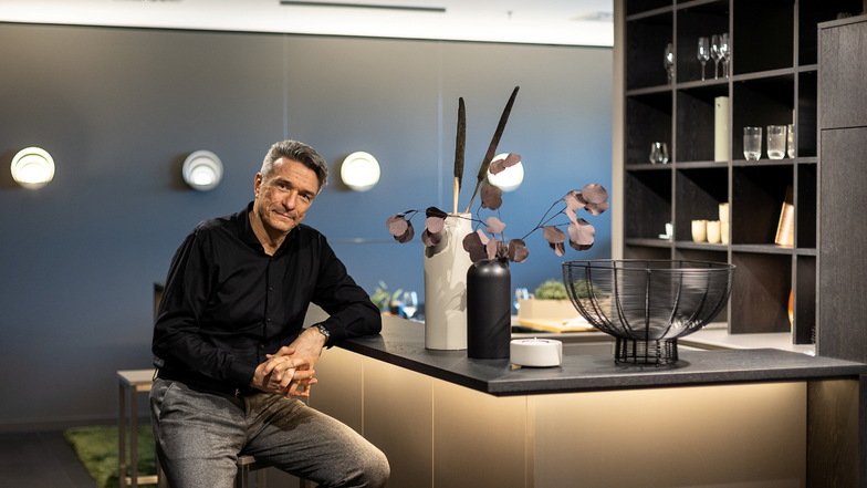 Hier sitzt Elko Beeg, der Geschäftsführer von Sachsenküchen in Obercarsdorf in einer Wohnküche in der Musterausstellung seines Unternehmens.